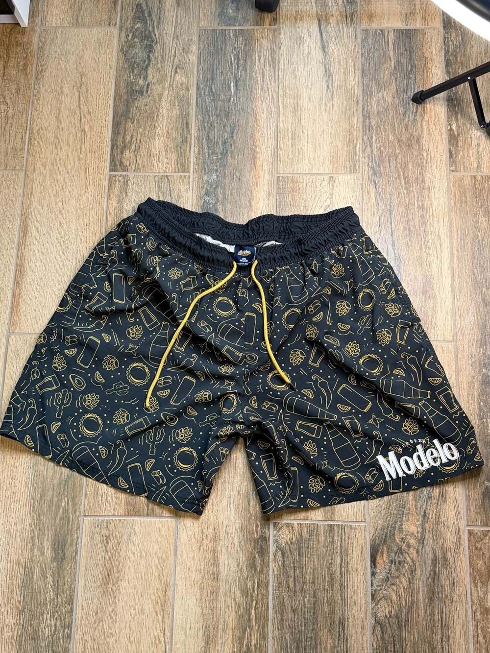 Modelo Cerveza Men's Graphic Allover Print Swim Trunks Board Shorts Black/Gold